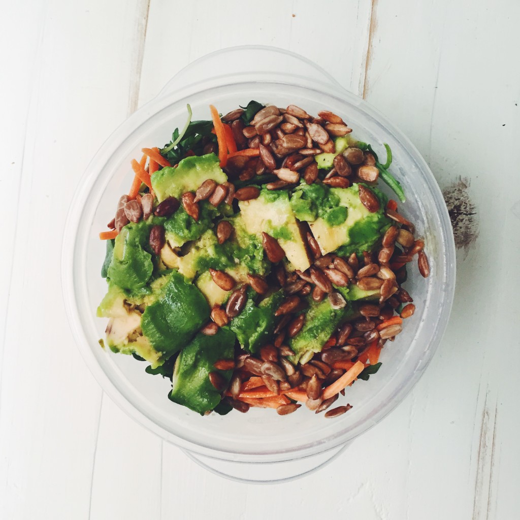 Arugula Salad topped with carrots, sunflower seeds, avocado and olive oil